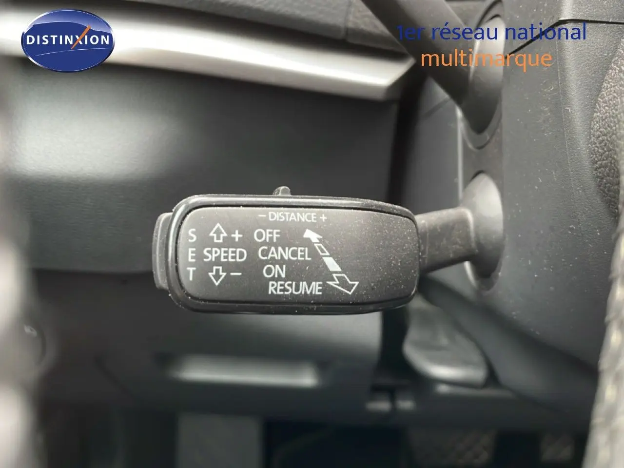 Gros plan sur la commande de régulateur de vitesse du Skoda Karoq blanc glacier, côté gauche du volant.