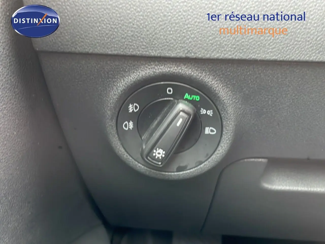 Gros plan sur le bouton de commande des phares du Skoda Karoq blanc glacier, avec mode automatique activé.