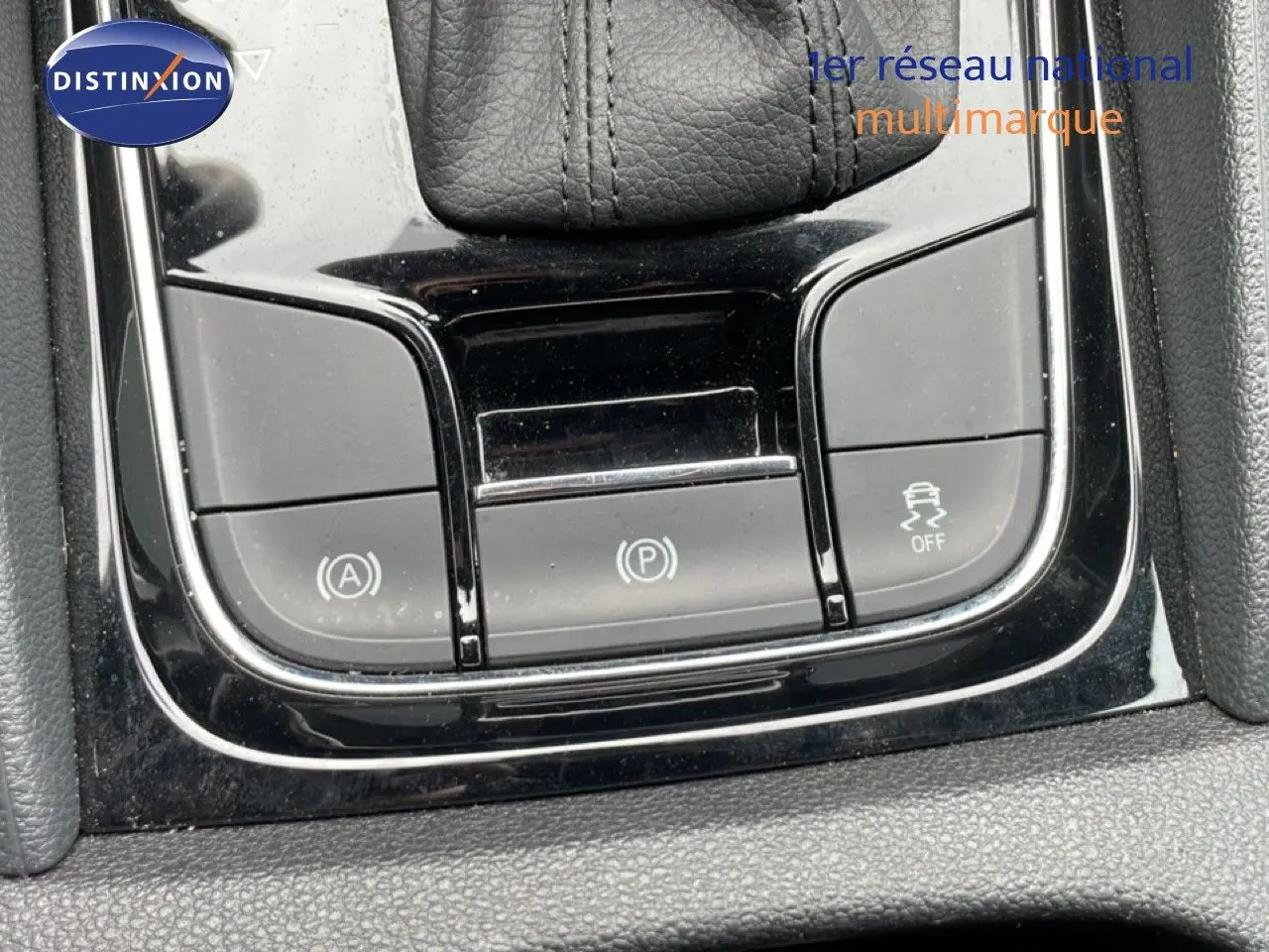 Gros plan sur les commandes de la console centrale noire du Skoda Karoq blanc glacier, avec levier de vitesse en cuir.