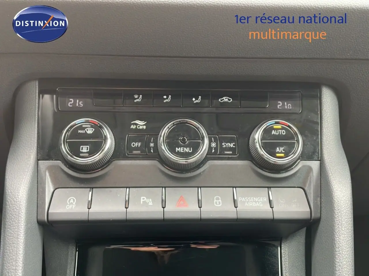 Gros plan sur la console centrale de la Skoda Karoq blanc glacier, montrant les commandes de climatisation et boutons fonctionnels.