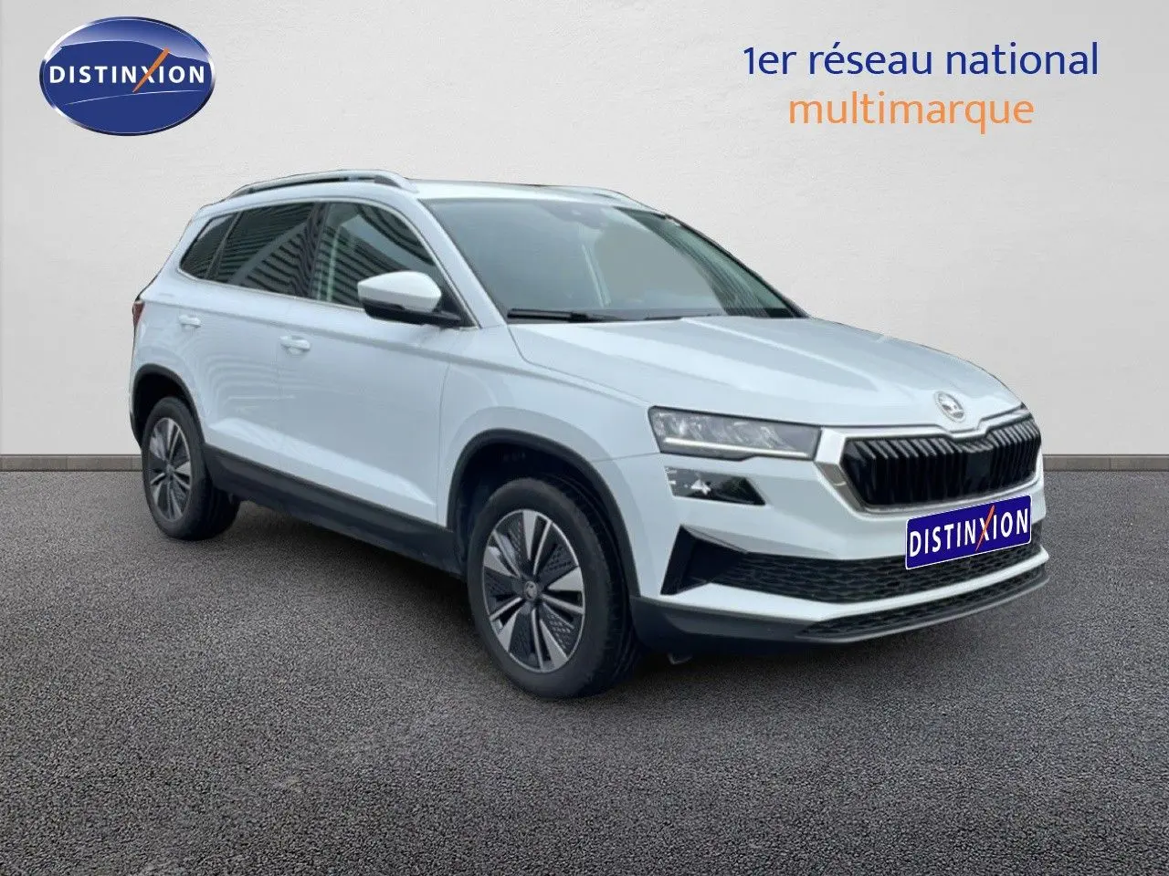 Vue 3/4 avant droit d'un Skoda Karoq blanc glacier avec calandre noire et jantes bi-ton.