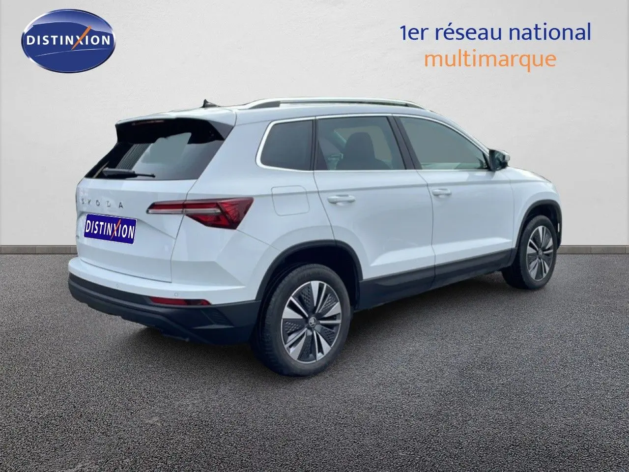 Vue 3/4 arrière droite du SUV SKODA KAROQ blanc glacier 2025 avec jantes bi-ton et feux arrière LED distinctifs.