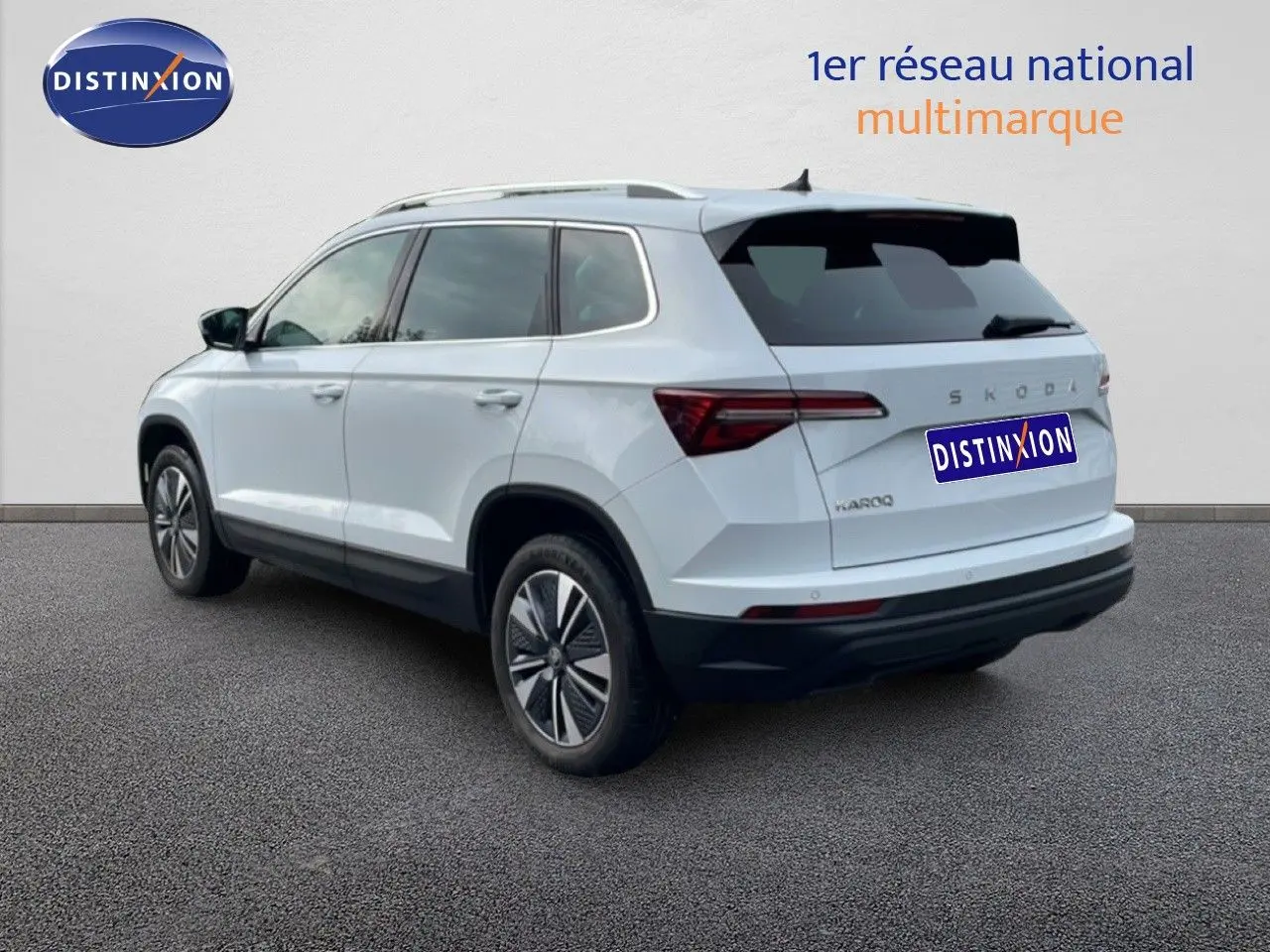 Vue 3/4 arrière droite d'un Skoda Karoq blanc glacier, SUV compact avec jantes bi-ton et feux arrière LED.