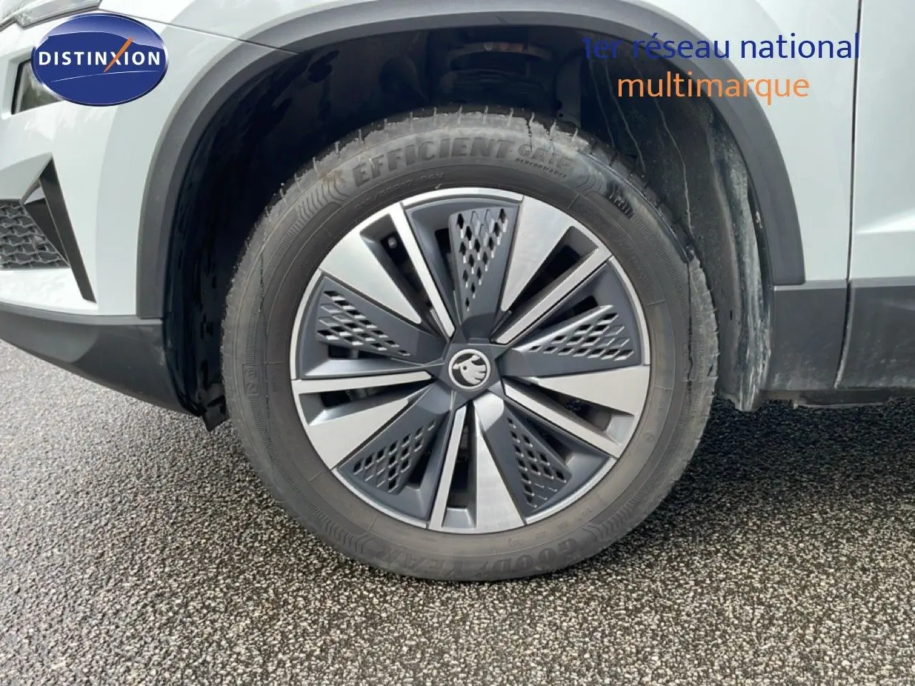 Gros plan sur la roue avant droite d’un Skoda Karoq blanc glacier, mettant en valeur la jante alliage au design moderne.