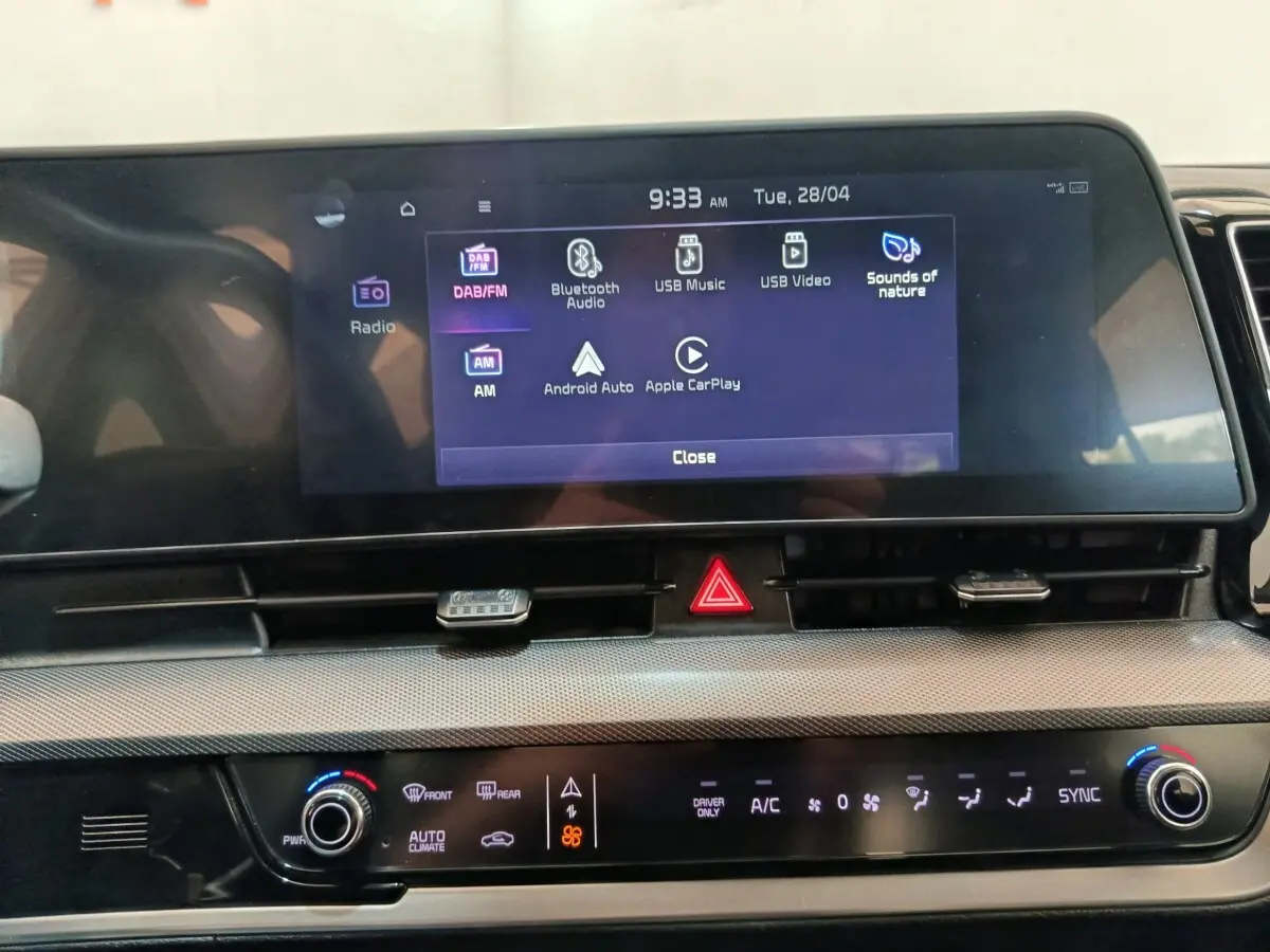 Vue rapprochée de l’écran tactile central du tableau de bord du Kia Sportage blanc, affichant les options multimédias.