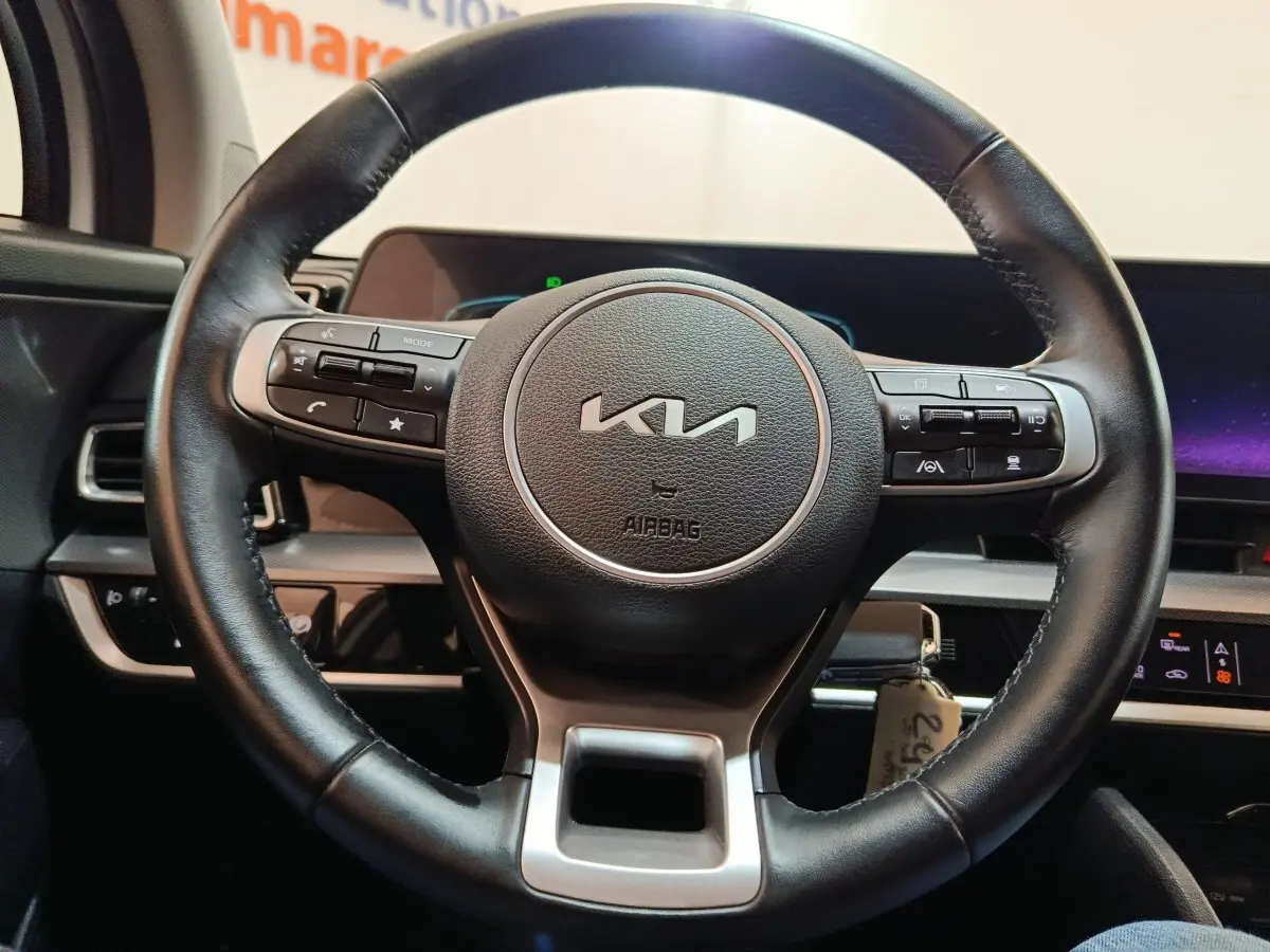Volant en cuir noir de KIA Sportage 2022 avec commandes intégrées, vue frontale sur tableau de bord digital.