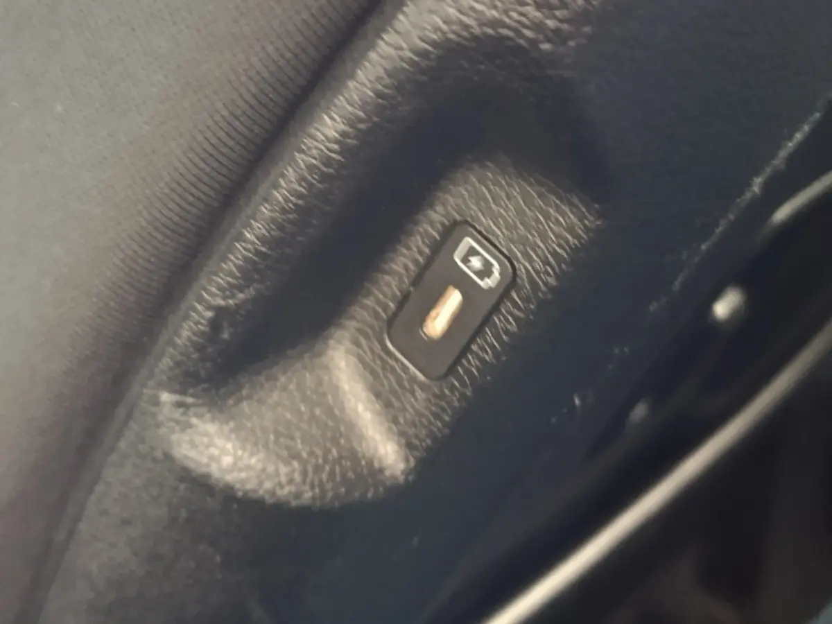 Gros plan sur le bouton de déverrouillage électrique de coffre, intérieur noir du Kia Sportage blanc 2022.