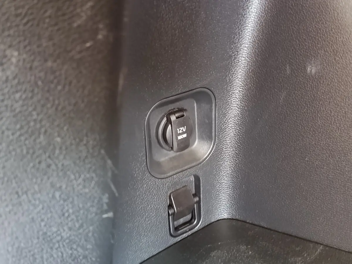 Prise 12V noire dans le coffre du Kia Sportage blanc, version hybride rechargeable 2022.