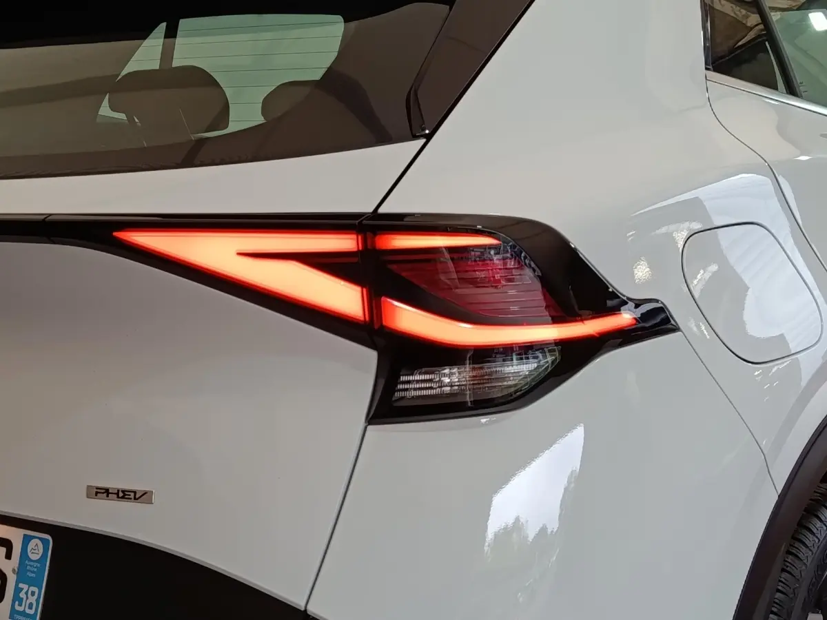 Gros plan sur le feu arrière droit allumé d’un KIA Sportage blanc hybride rechargeable avec logo PHEV visible.