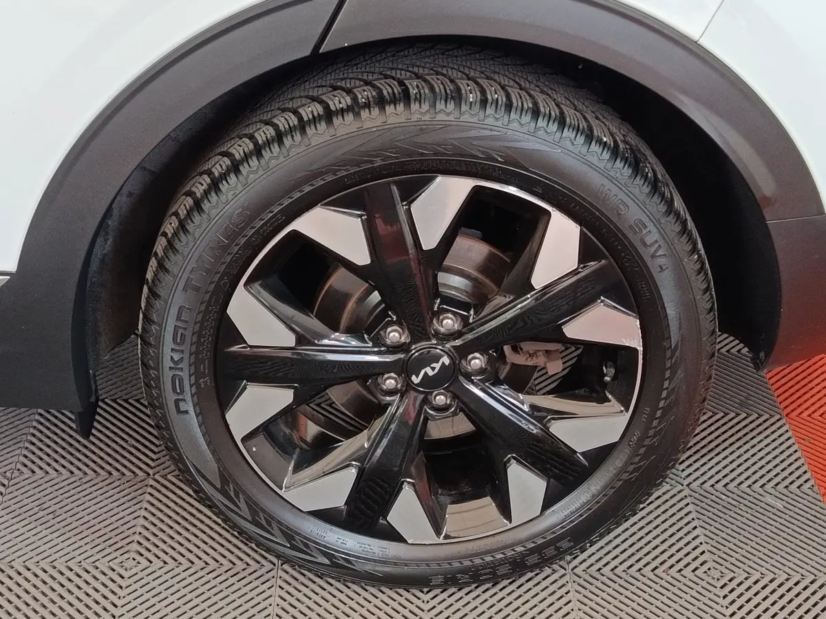 Gros plan sur la roue avant droite du KIA Sportage blanc, mettant en valeur la jante noire et argentée au design moderne.
