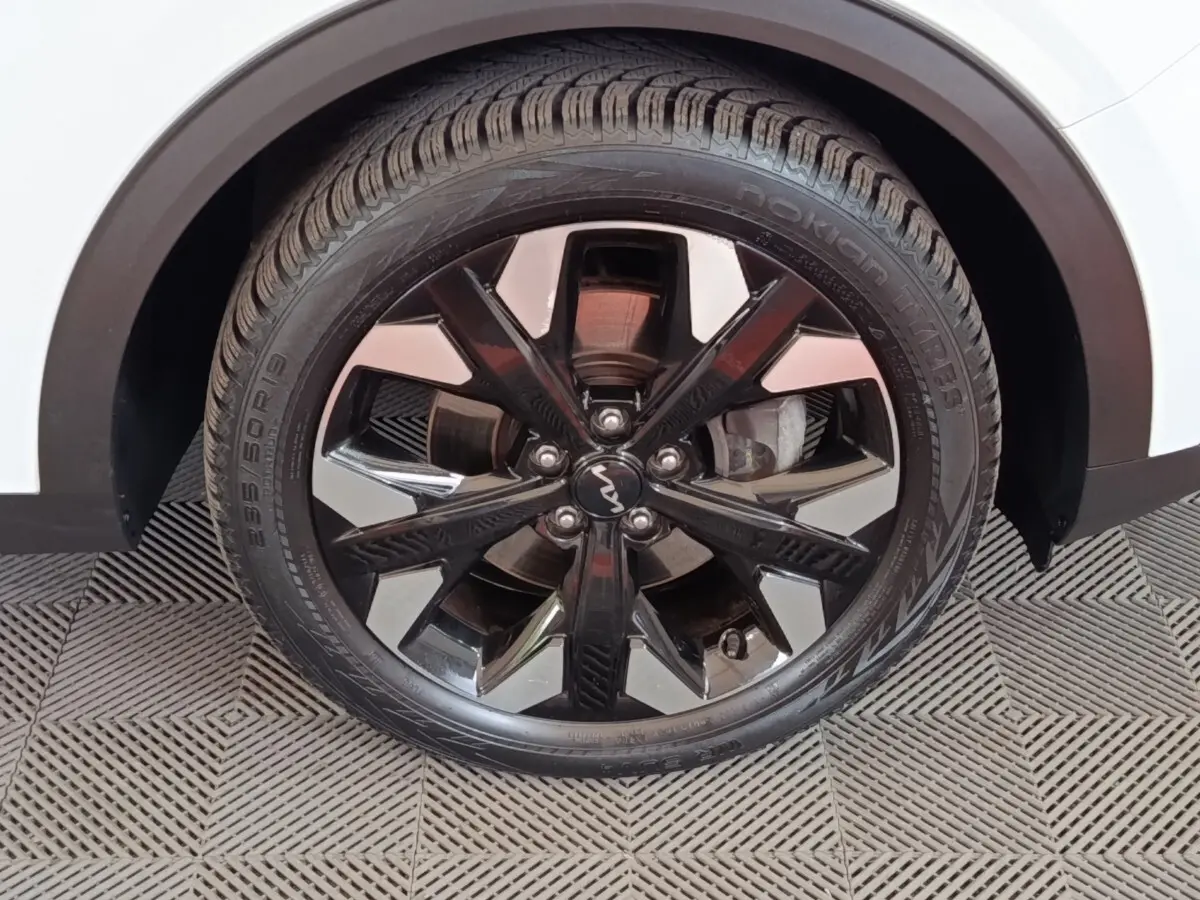 Gros plan sur la roue arrière droite noire et chromée du KIA SPORTAGE blanc 2022, jante alliage distinctive.