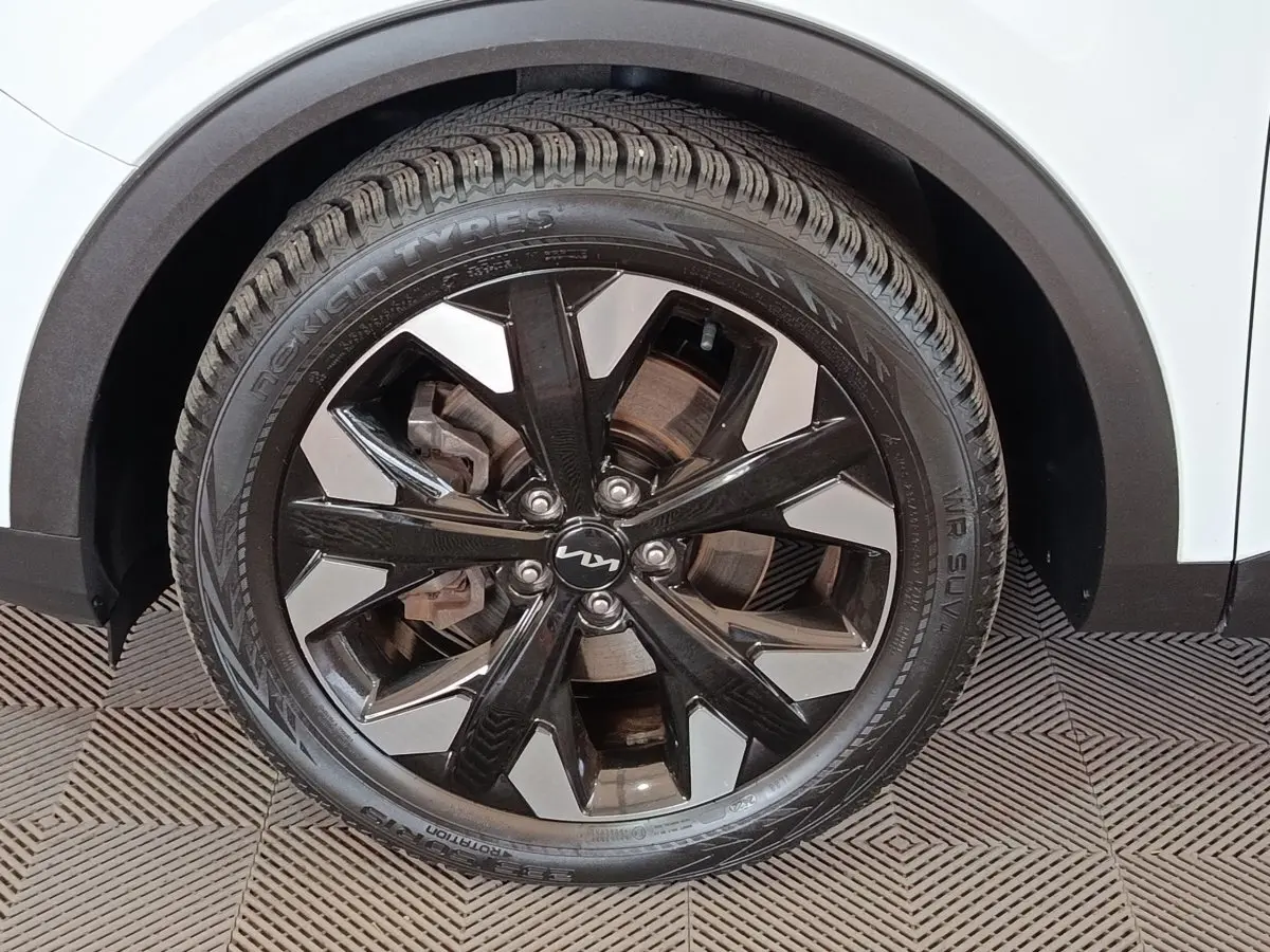 Gros plan sur la roue avant droite du Kia Sportage blanc 2022 avec jante alliage noire et argentée design moderne.