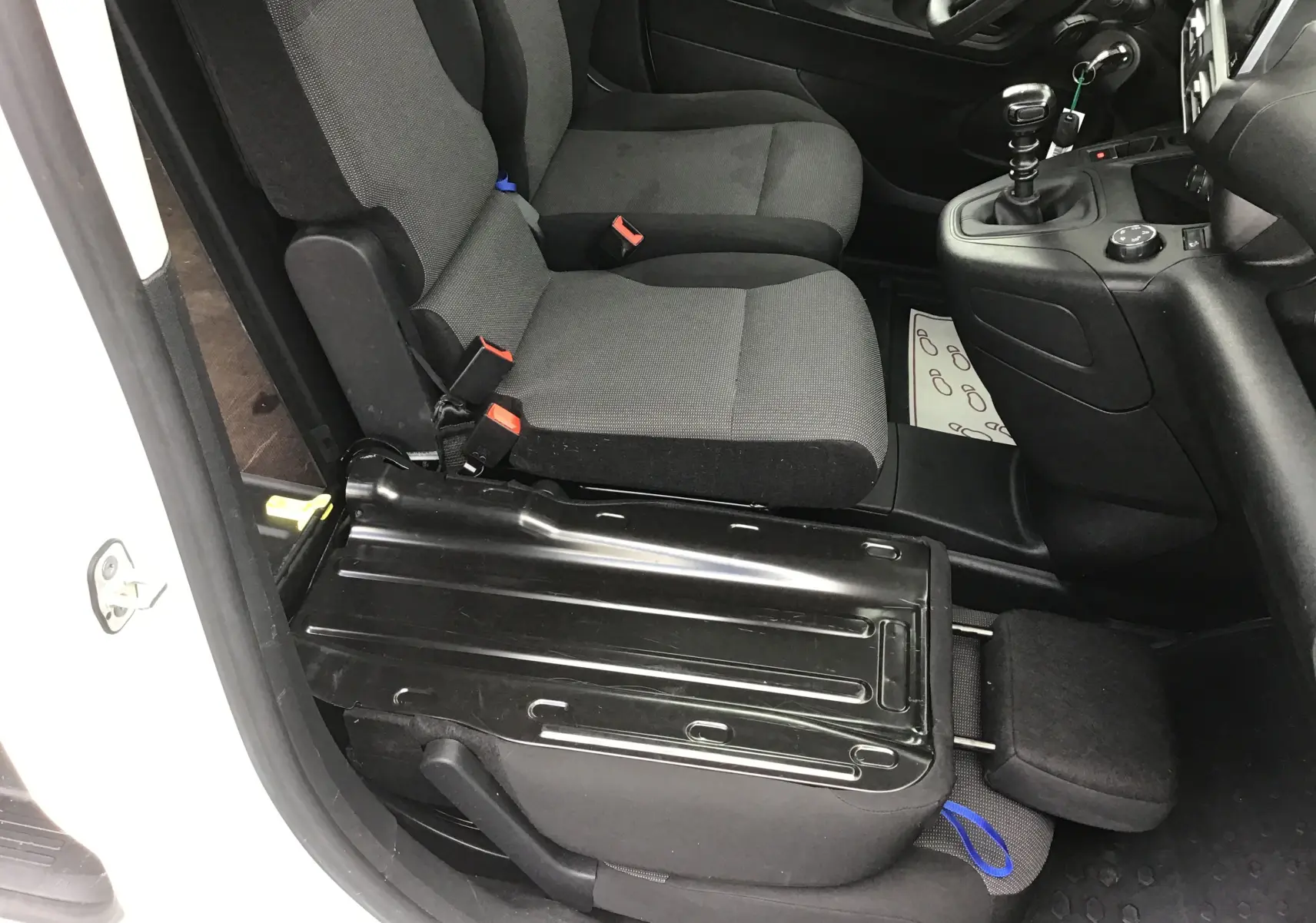 Vue intérieure côté gauche du Peugeot Partner blanc 2022, montrant les sièges avant et la console centrale avec boîte manuelle.