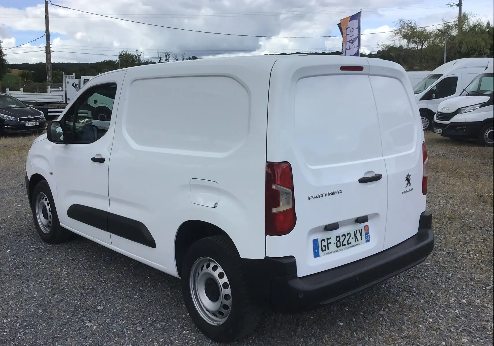 Vue 3/4 arrière droite d’un Peugeot Partner blanc utilitaire avec porte latérale et plaque d’immatriculation française.