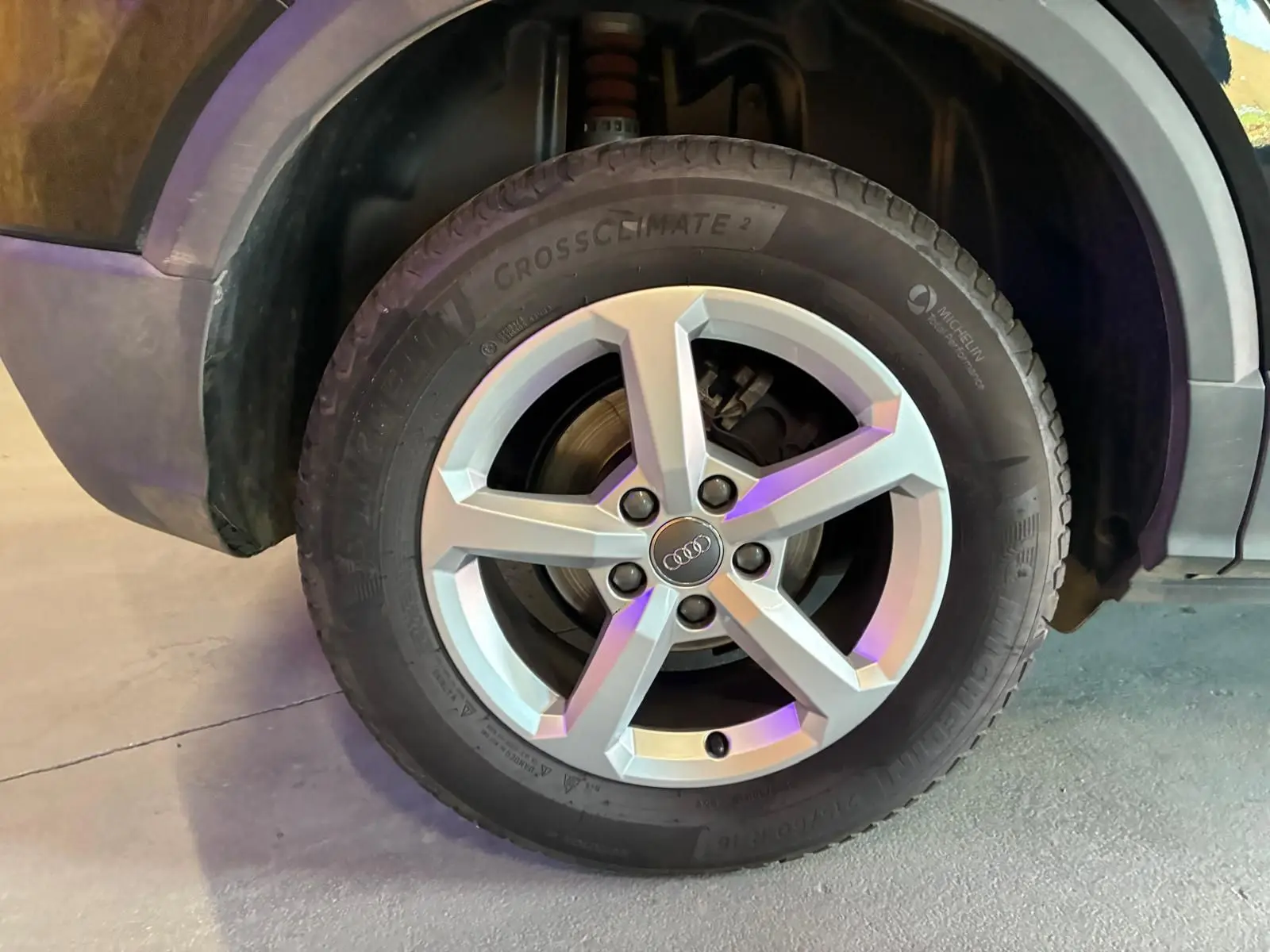 Gros plan sur la roue avant droite d’un Audi Q2 noir, mettant en valeur la jante argentée à cinq branches.