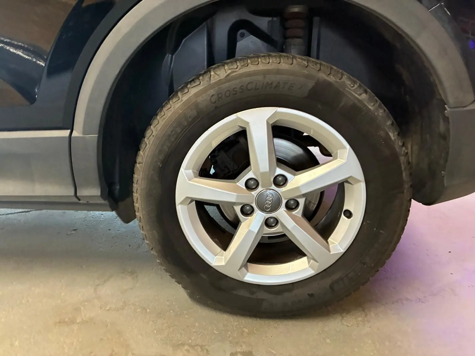 Gros plan sur la roue avant droite d’un Audi Q2 noir, mettant en valeur la jante argentée à cinq branches.
