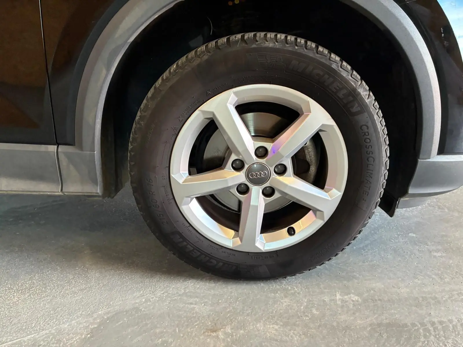 Gros plan sur la roue avant droite d’un Audi Q2 noir, mettant en valeur la jante argentée à cinq branches et le pneu Michelin.