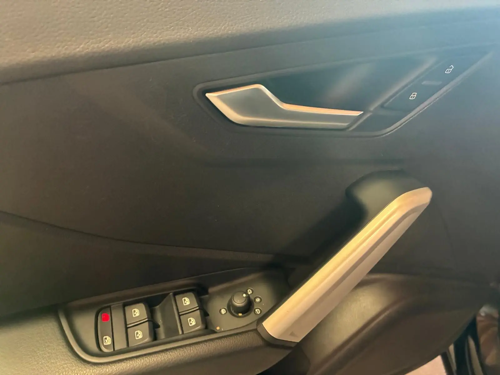 Détail de la porte intérieure côté conducteur d’un Audi Q2 noir, avec commandes des vitres et poignée argentée.