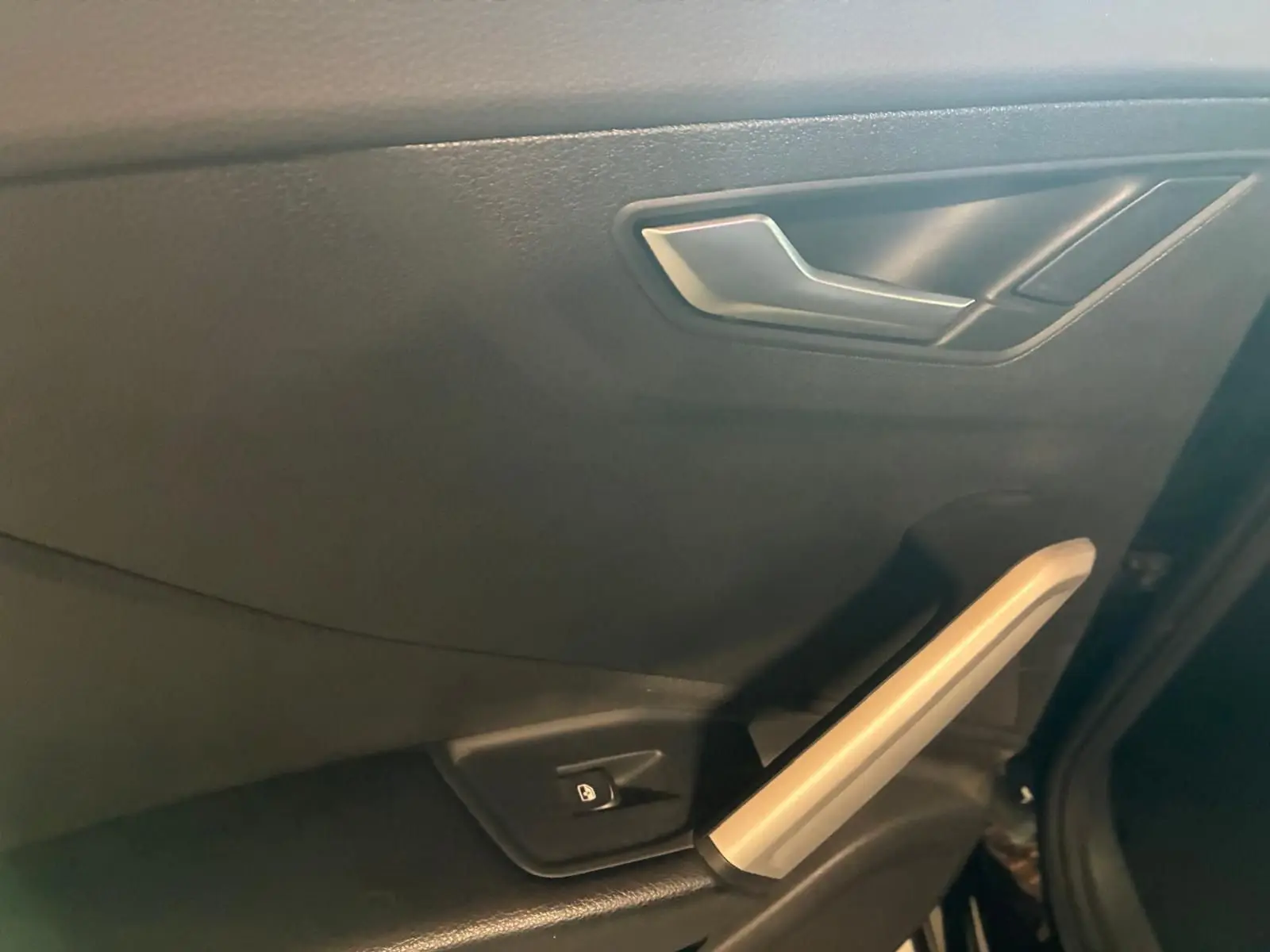 Gros plan sur la poignée intérieure et le bouton de verrouillage de la porte côté gauche d’un Audi Q2 noir de 2020.
