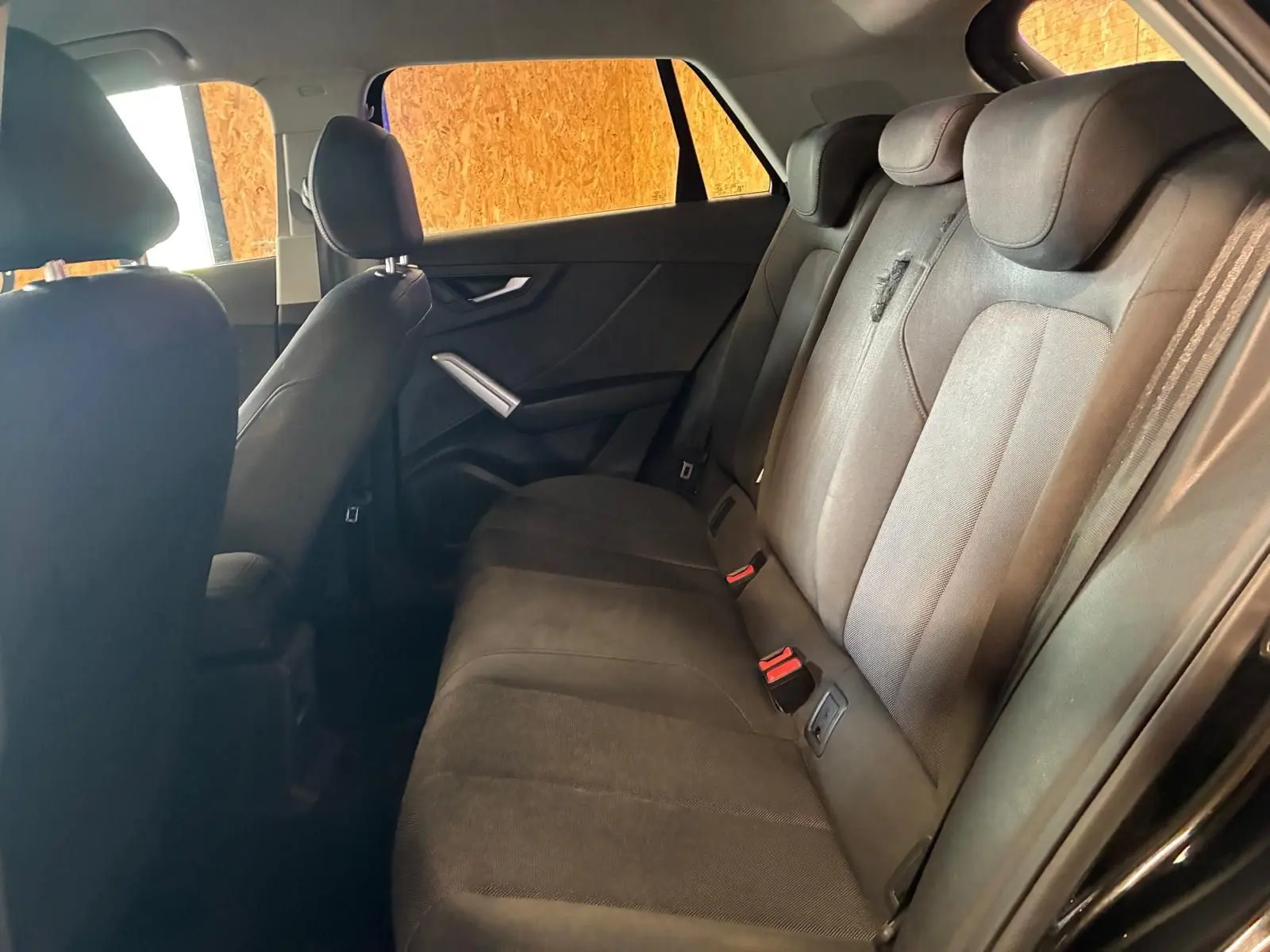 Vue intérieure côté droit des sièges arrière noirs en tissu de l'Audi Q2 30 1.6 TDI 2020 avec ceintures visibles.