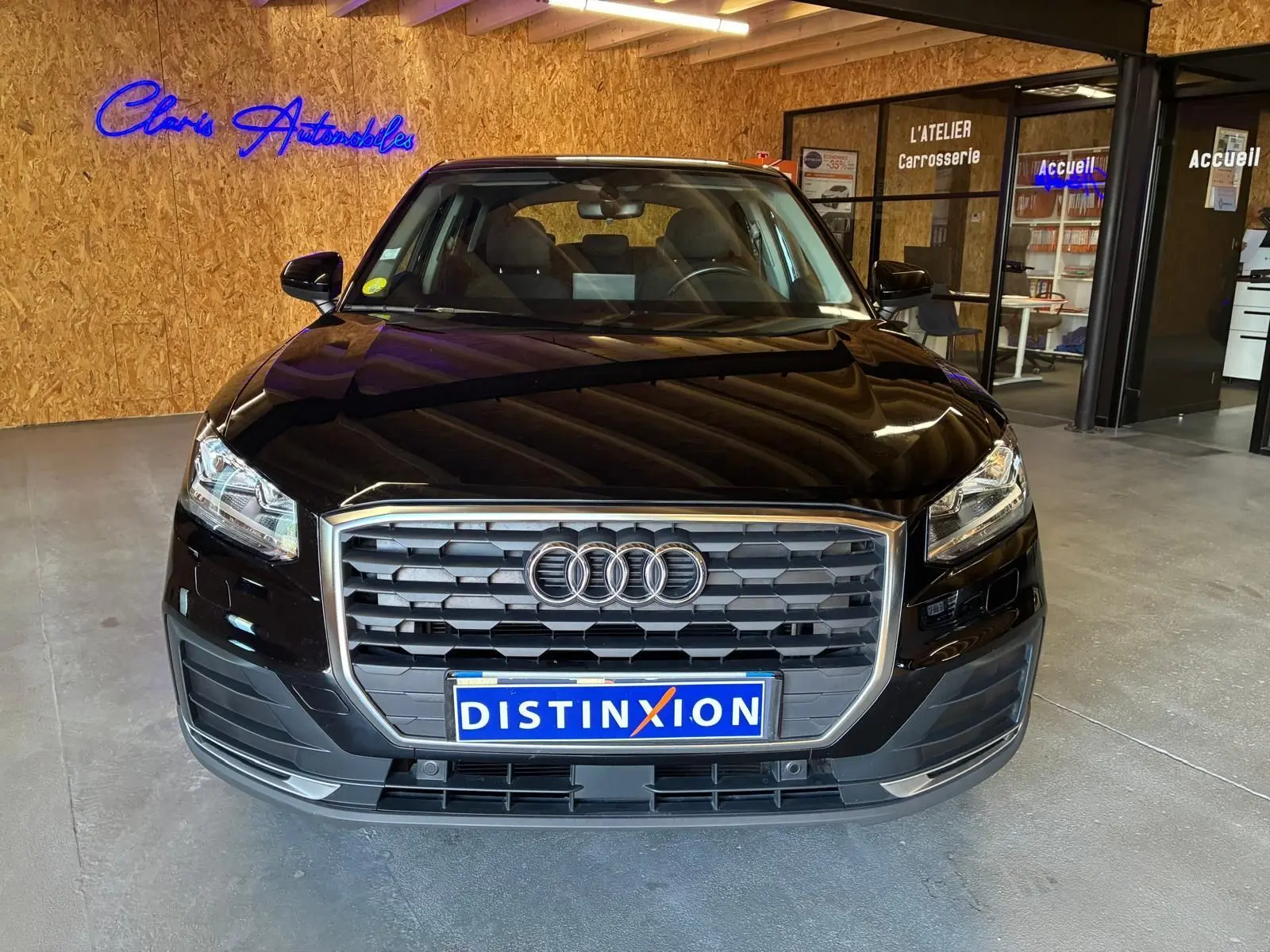 Vue avant d'un Audi Q2 noir 2020 avec calandre hexagonale et logo Audi, en intérieur dans un showroom.