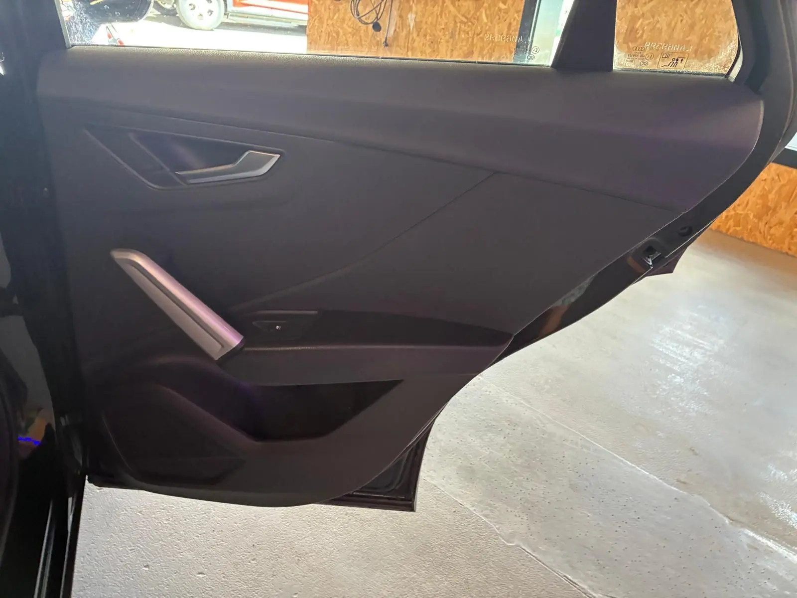 Vue intérieure de la porte arrière gauche noire d’un Audi Q2 30 1.6 TDI 2020 avec poignée argentée et garniture tissu noire.