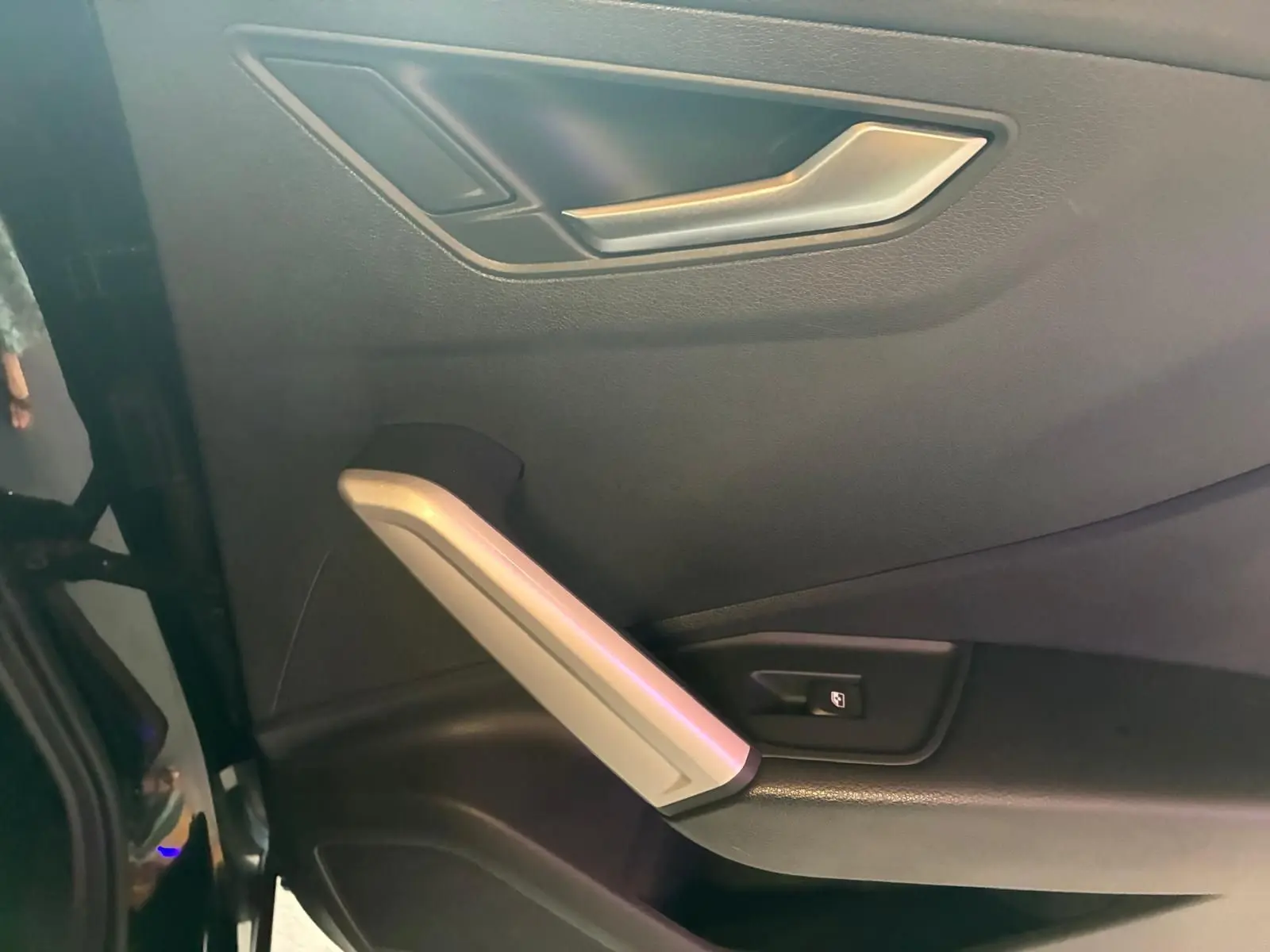Détail de la porte intérieure côté gauche d’un Audi Q2 noir, avec poignée argentée et bouton de verrouillage.