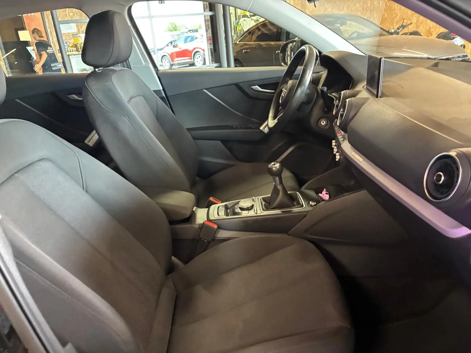 Intérieur noir de l'Audi Q2 30 1.6 TDI 2020 vu côté droit, mettant en valeur la boîte manuelle et le tableau de bord.