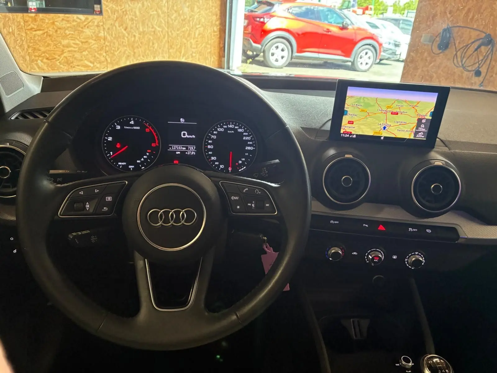 Vue intérieure centrée sur le volant noir d’un Audi Q2 2020 avec tableau de bord digital et écran GPS en surplomb.