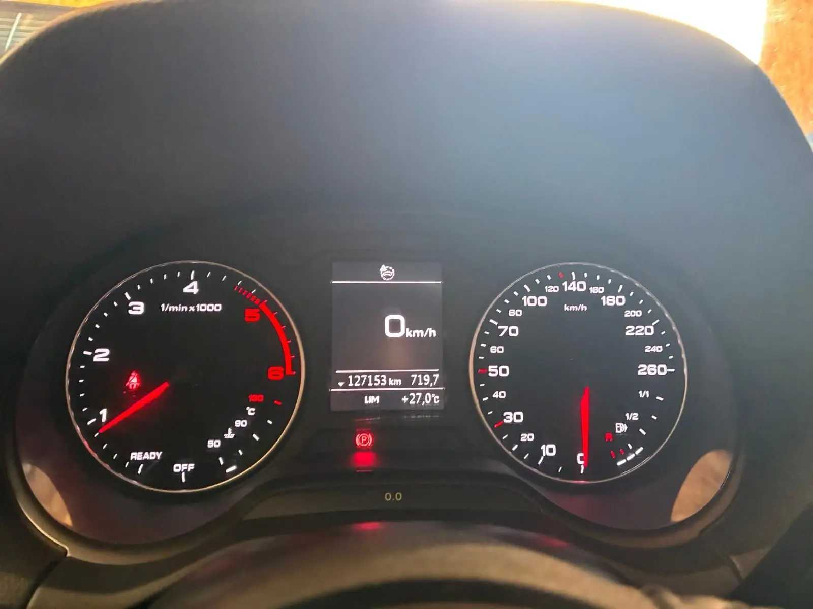 Vue rapprochée du tableau de bord noir d’un Audi Q2 30 1.6 TDI 2020, affichant 0 km/h et 127153 km au compteur.