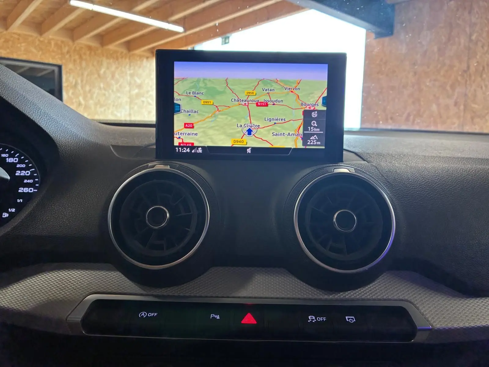 Vue intérieure centrée sur le tableau de bord noir de l'Audi Q2 2020, avec écran GPS et aérateurs ronds visibles.