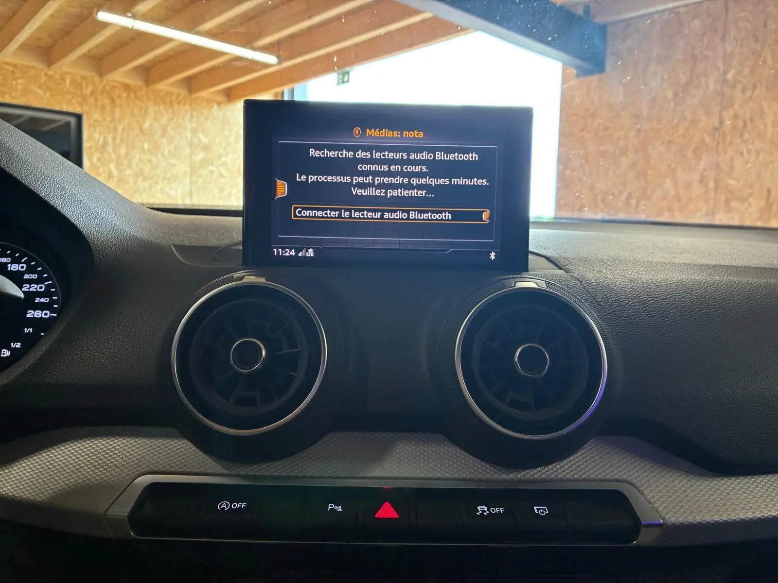 Vue rapprochée de la console centrale de l’Audi Q2 noire, avec écran multimédia et aérateurs ronds visibles.