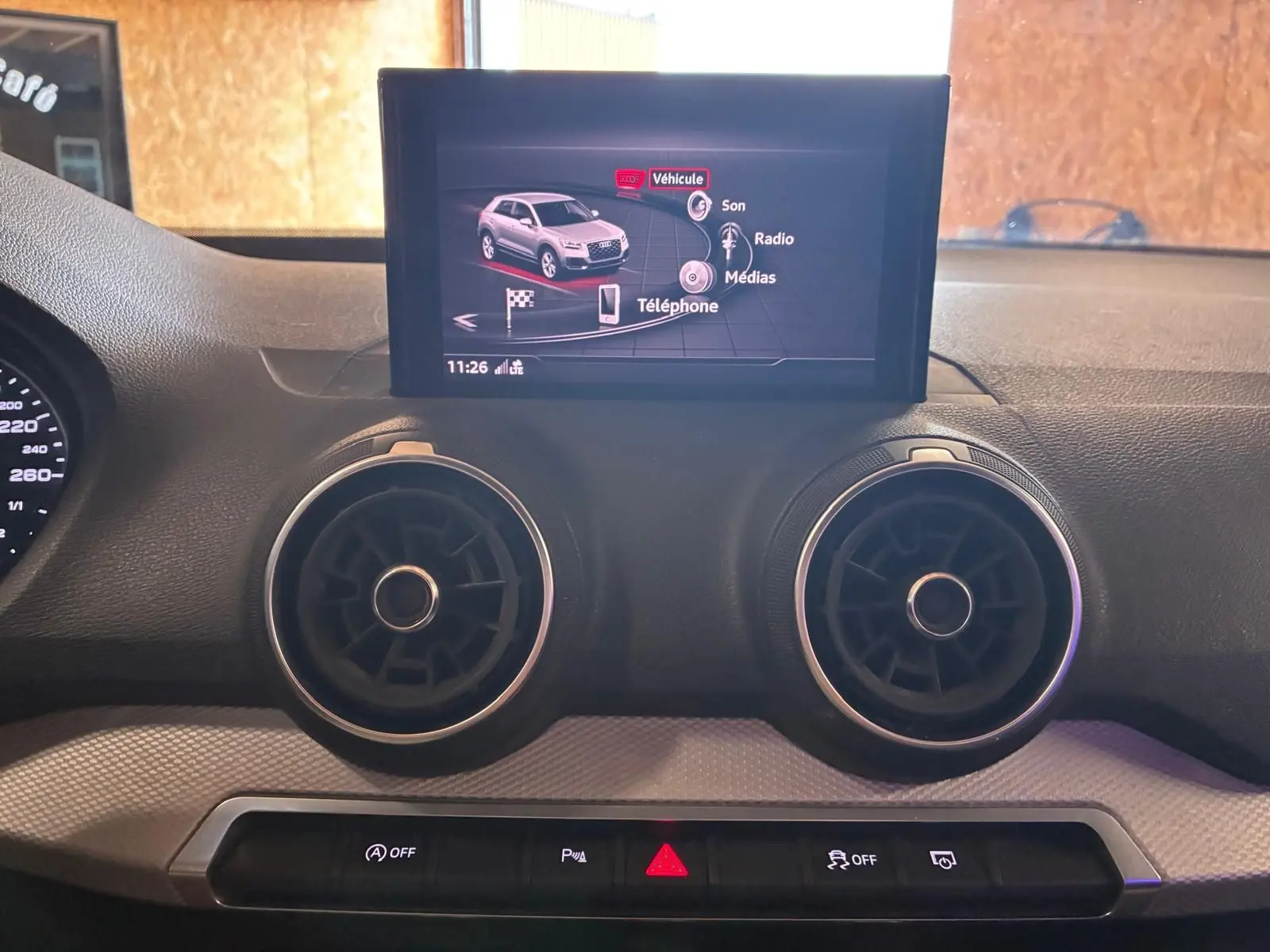 Vue intérieure du tableau de bord de l'Audi Q2 noir 2020, avec écran central et aérateurs ronds visibles.
