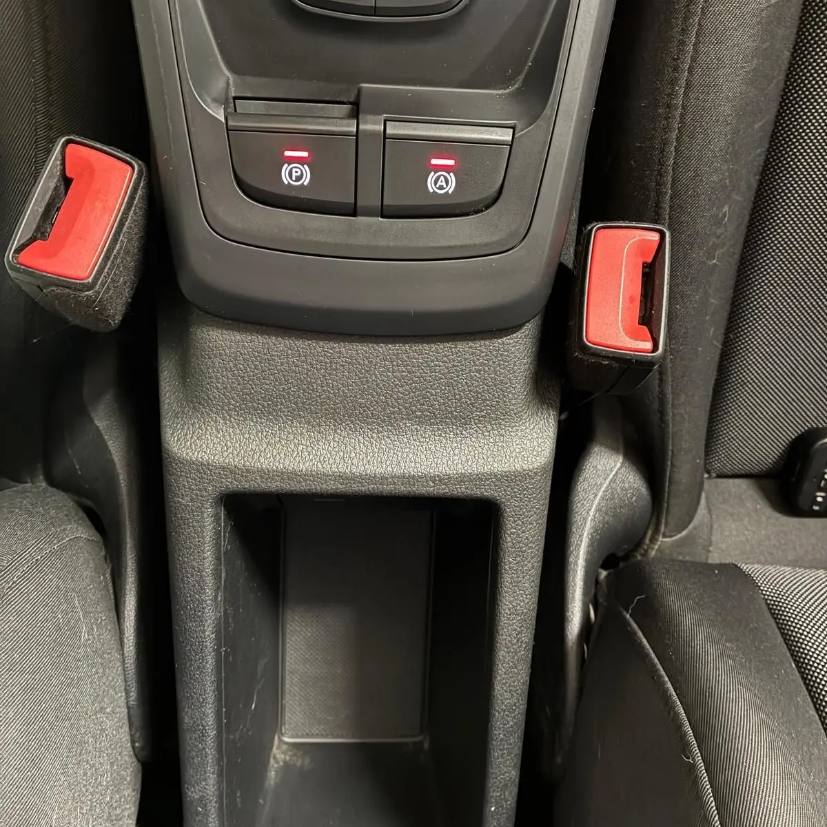 Vue rapprochée de la console centrale noire de l'Audi Q2 2020, avec boutons de frein à main et arrêt automatique éclairés.