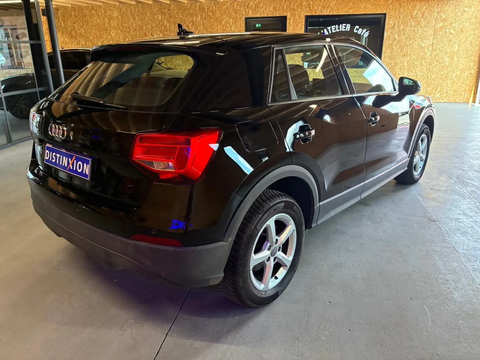 Audi Q2 noire vue 3/4 arrière droit, mettant en valeur ses feux arrière rouges et ses jantes alliage argentées.
