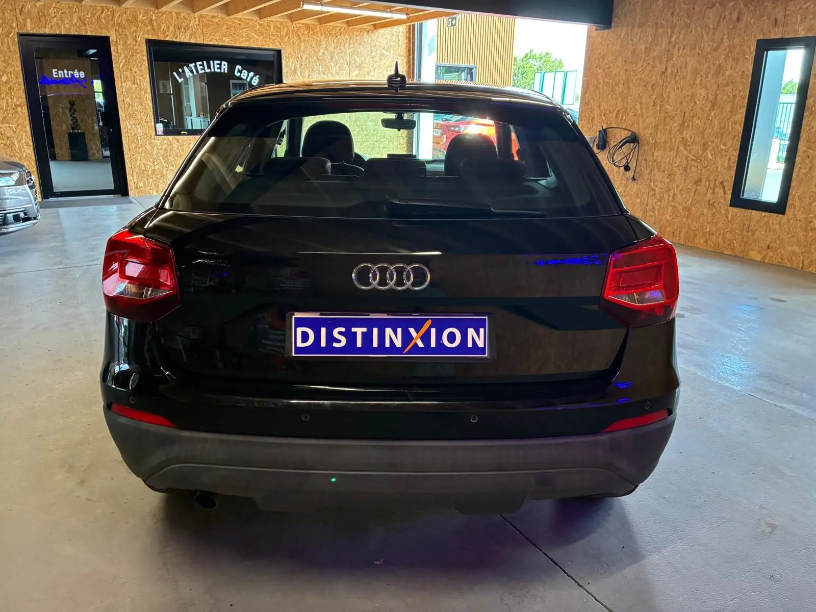 Vue arrière d'un Audi Q2 noir de 2020, stationné en intérieur avec logo Audi et plaque Distinxion visible.