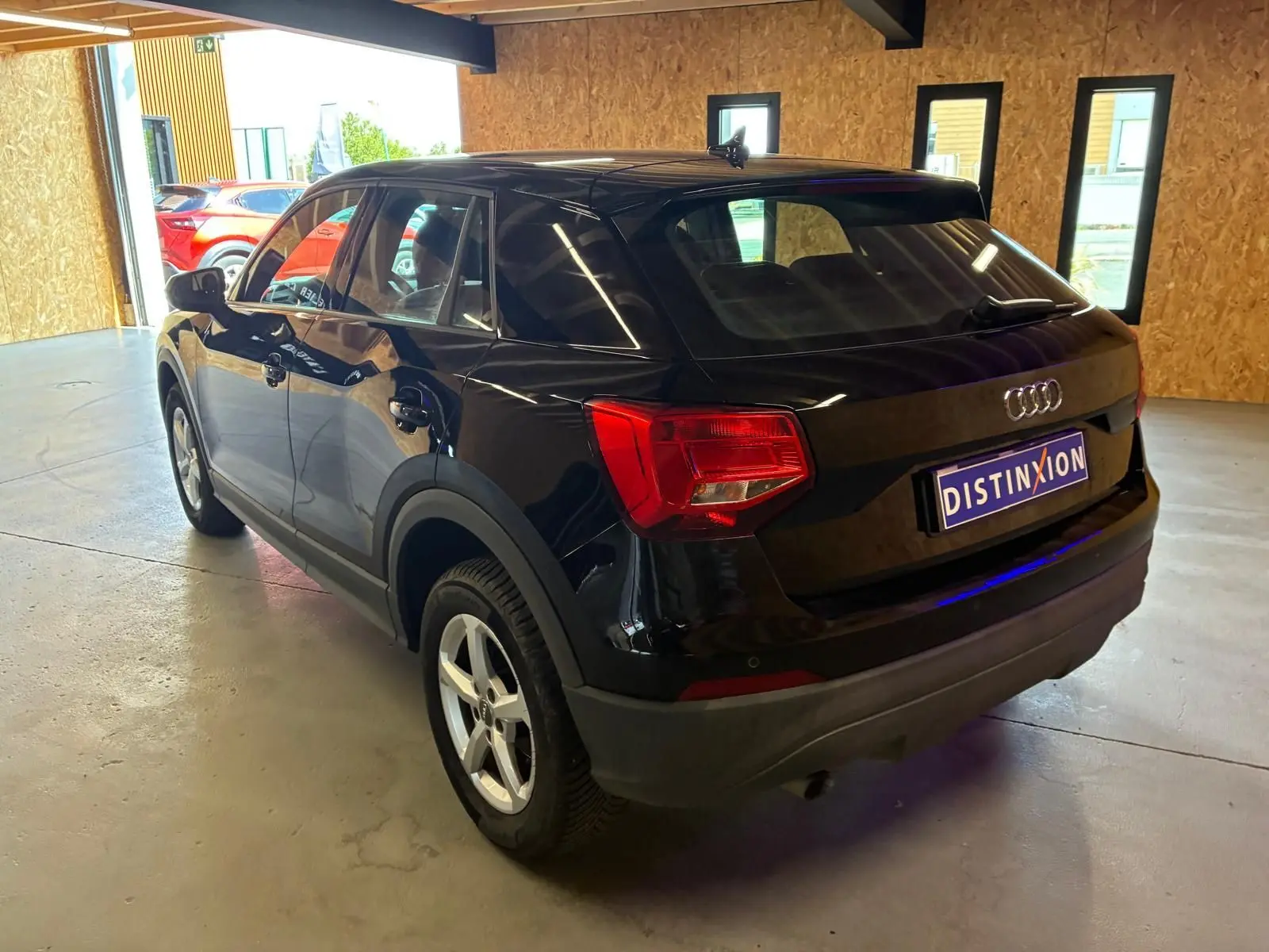 Audi Q2 noir vue 3/4 arrière droit dans un garage, avec feux arrière rouges et jantes argentées.