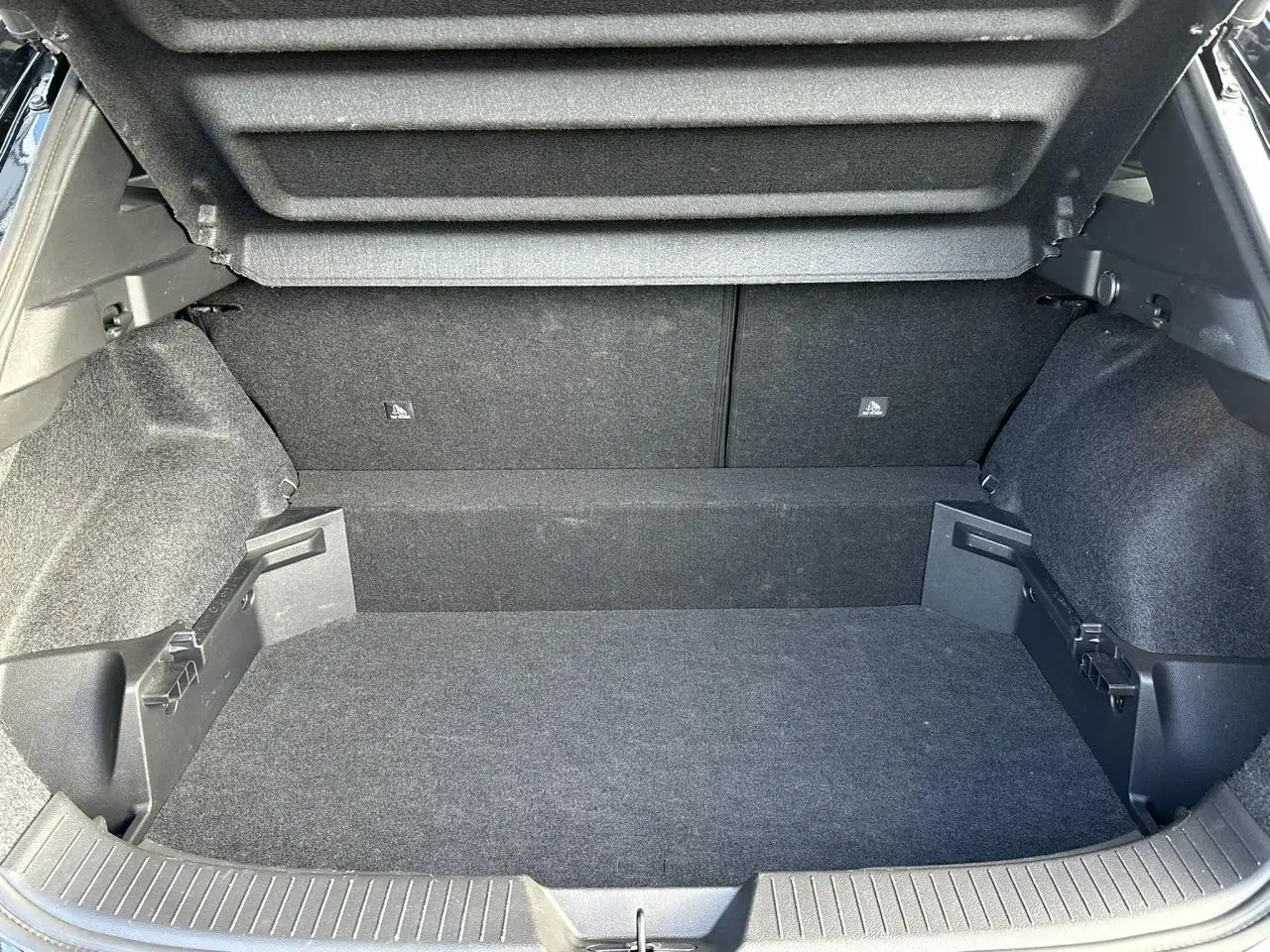 Coffre ouvert du Nissan Qashqai III noir nacré, montrant le plancher modulable et les côtés tapissés en tissu gris.