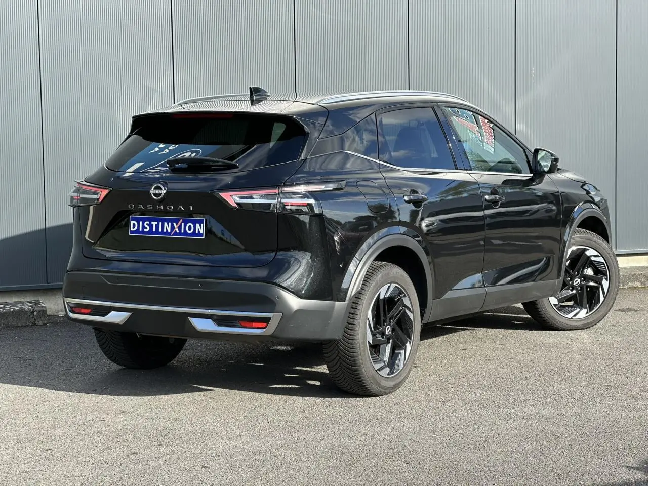 Nissan Qashqai noir nacré en 3/4 arrière droit, avec jantes alliage noires et hayon électrique visible.