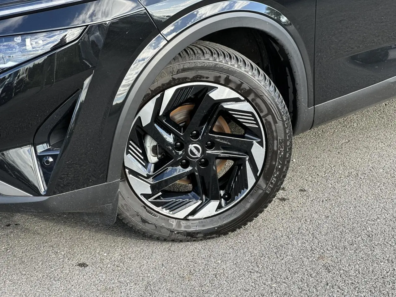 Gros plan sur la roue avant gauche noire nacrée du Nissan Qashqai 2025 avec jante alliage bicolore et détails modernes.