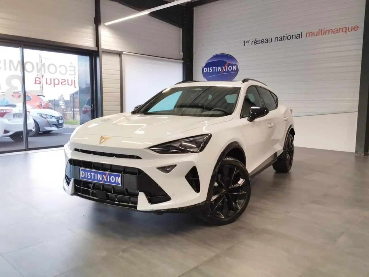 Vue 3/4 avant d'un CUPRA Formentor blanc Nevada avec jantes noires et détails contrastés noirs dans un showroom.