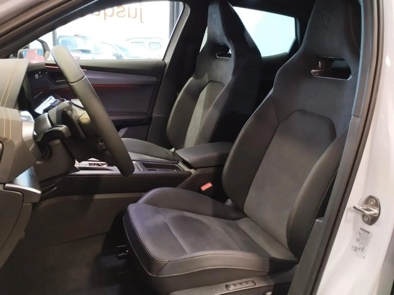 Vue intérieure côté conducteur du CUPRA Formentor blanc Nevada avec sièges baquets suédine noire et surpiqûres cuivrées.