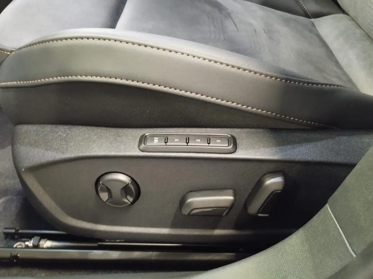 Gros plan sur les commandes électriques du siège conducteur en suédine noire avec surpiqûres cuivrées du CUPRA Formentor blanc.
