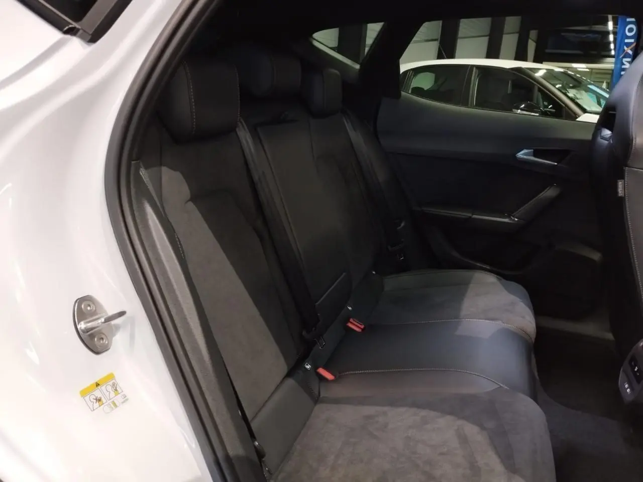 Vue intérieure côté arrière gauche du CUPRA Formentor blanc Nevada avec sièges baquets suédine noire et surpiqûres cuivrées.