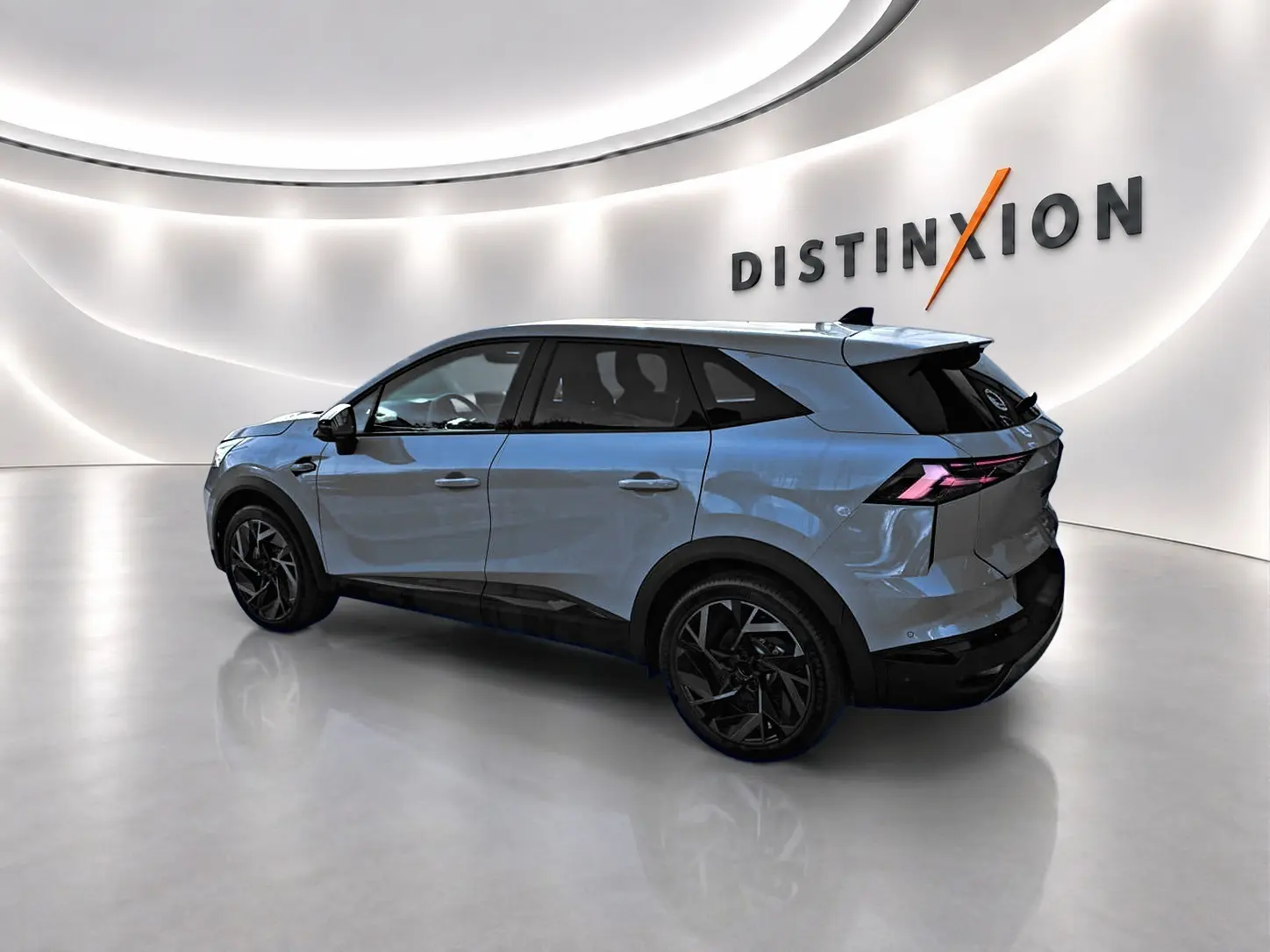 Renault Symbioz gris rafale en vue 3/4 arrière droit dans un showroom lumineux avec jantes noires distinctives.
