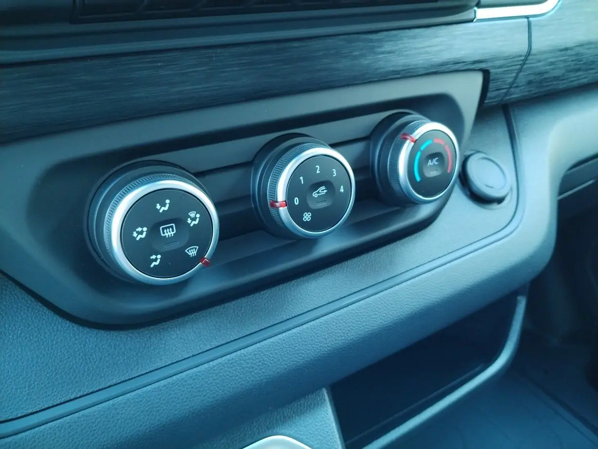 Gros plan sur les commandes de climatisation du tableau de bord du Nissan Primastar blanc 2025 avec pack bois.