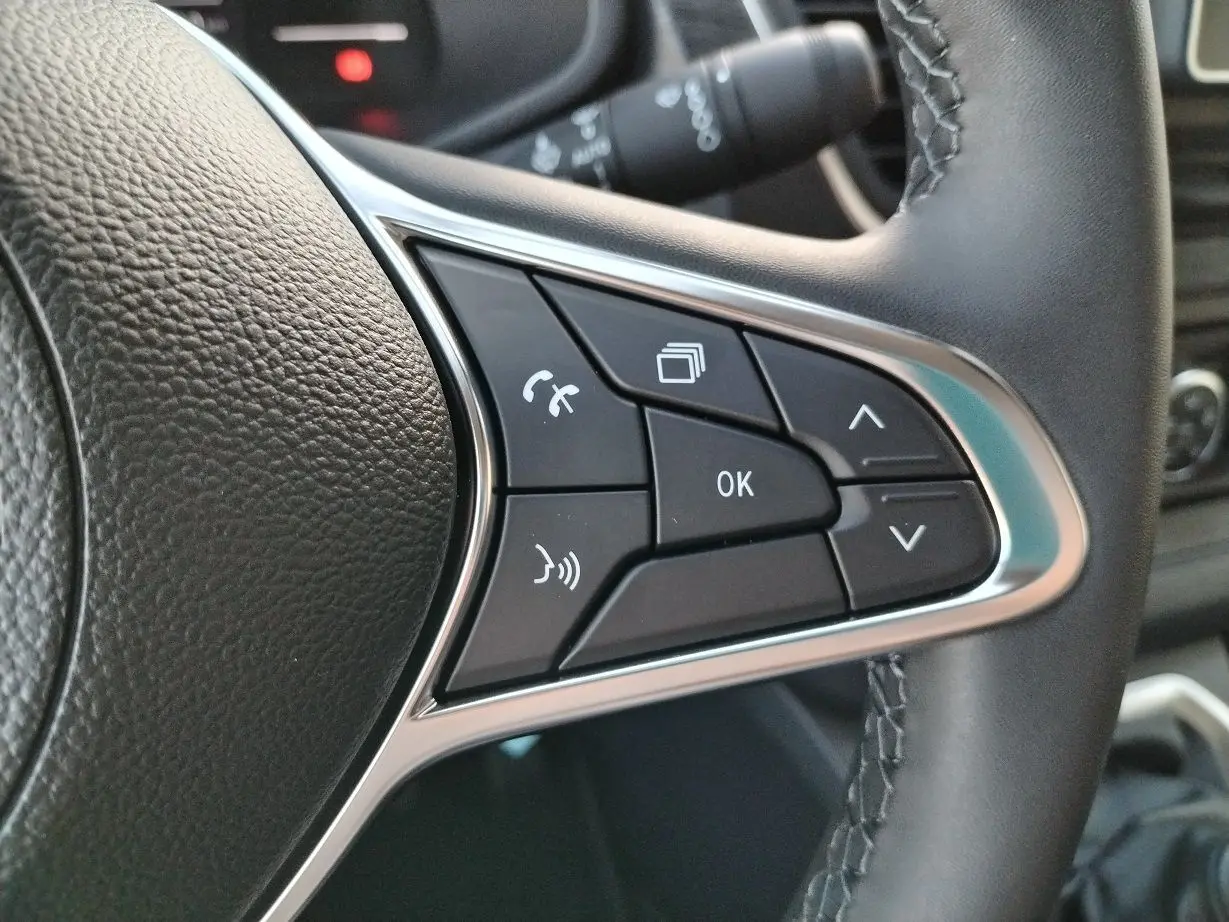 Gros plan sur les commandes multifonctions noires et argentées du volant en cuir du Nissan Primastar blanc 2025.