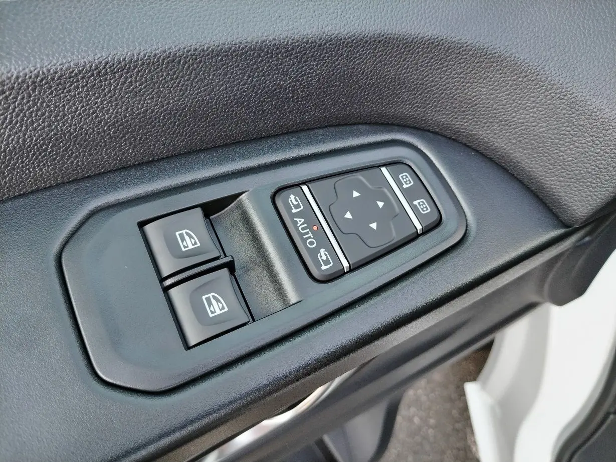 Gros plan sur les commandes de lève-vitres et réglage des rétroviseurs côté conducteur du Nissan Primastar blanc 2025.