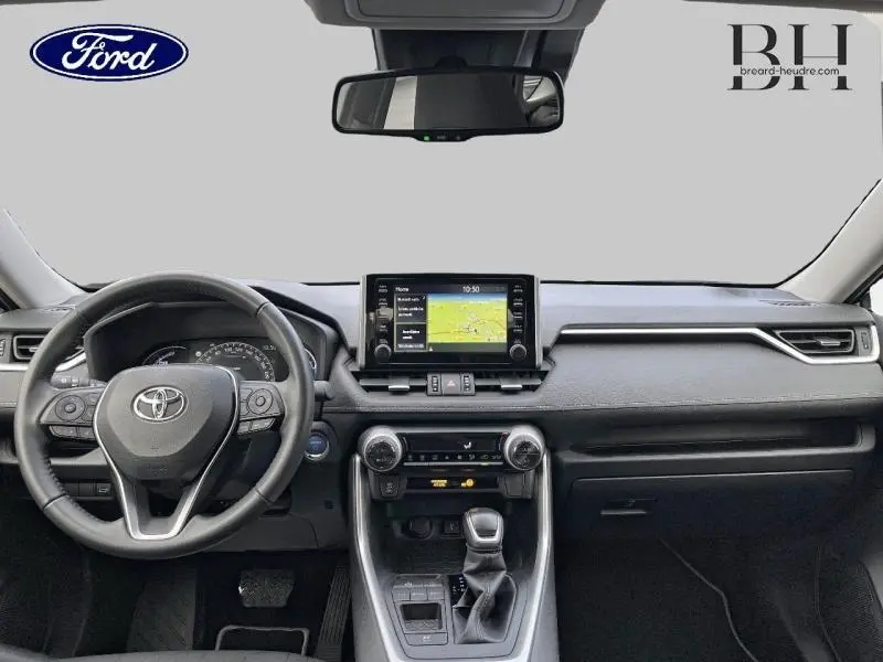 Vue intérieure frontale du tableau de bord du Toyota RAV4 2.5 Hybride 2022 avec écran tactile GPS et volant multifonction cuir.