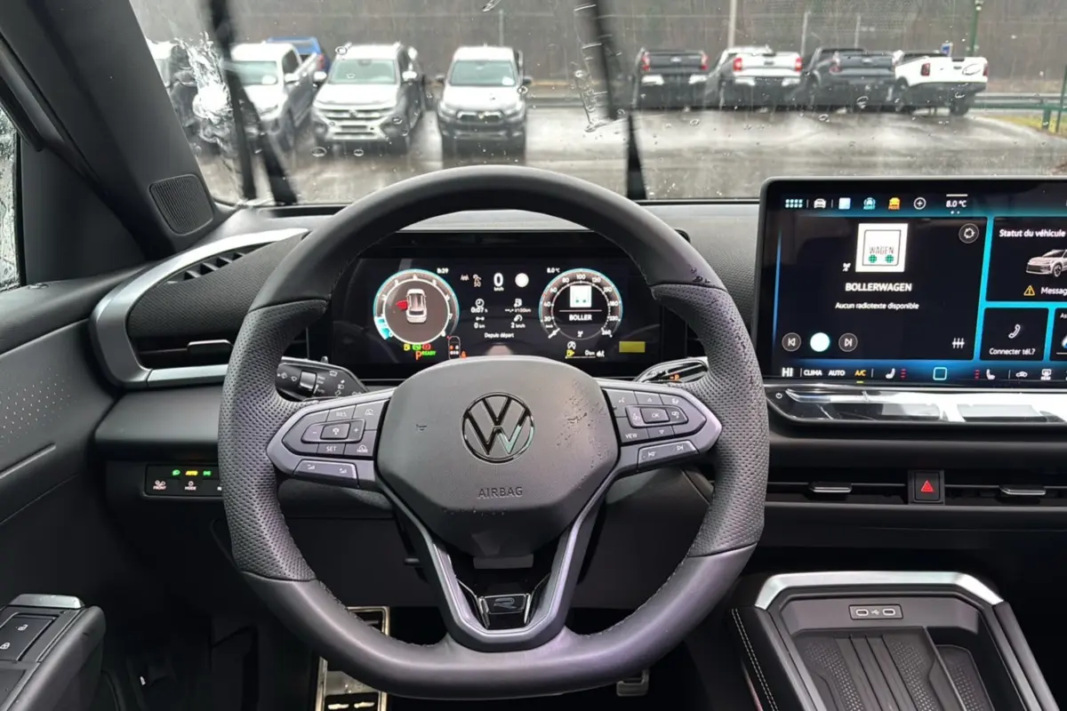 Vue frontale du tableau de bord et volant cuir multifonctions du Volkswagen T-Roc blanc toit noir, avec écran digital et commandes tactiles.